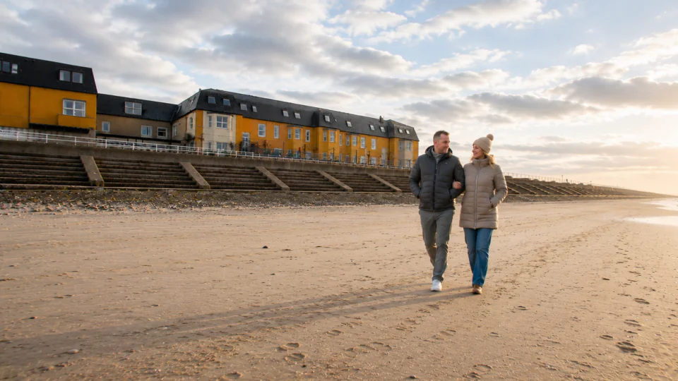 couple in coats walking on the beach